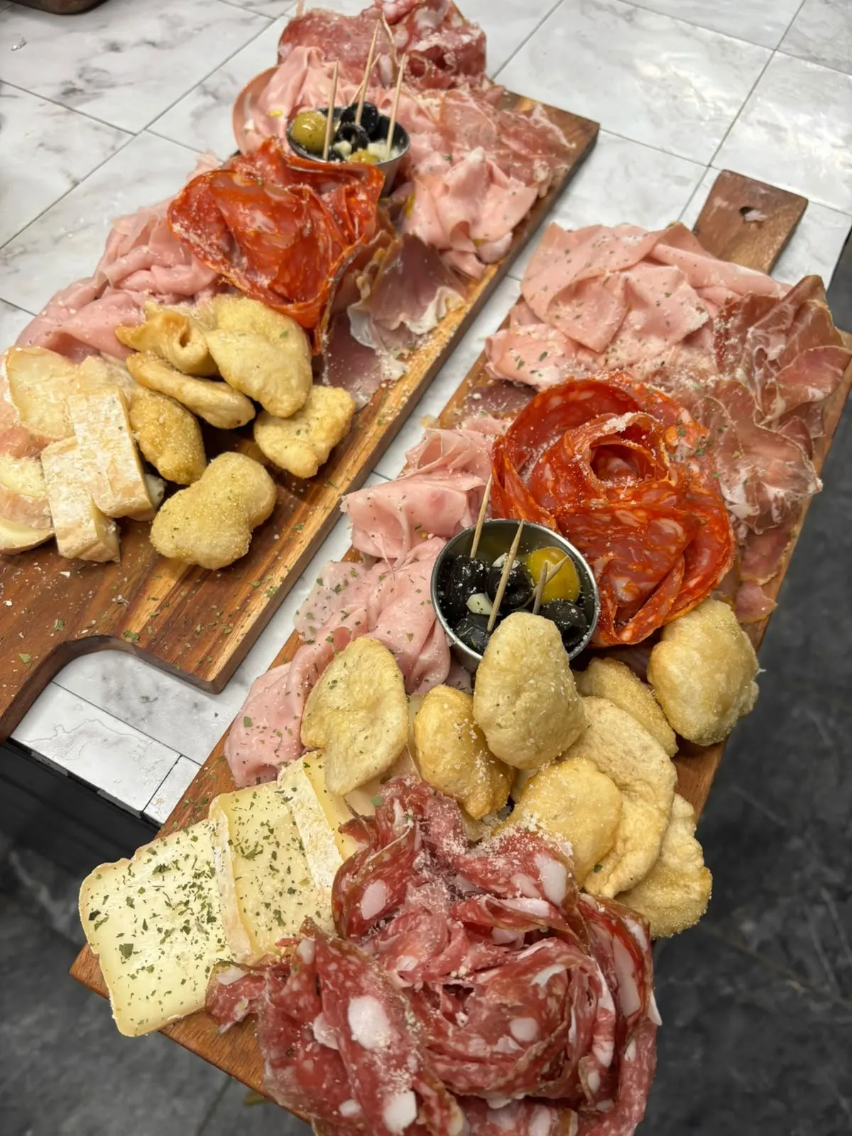 Deux planches de charcuterie italienne, avec fromages, olives et beignets dorés